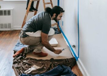 Un professionista utilizza un rullo per pitturare le pareti esterne di un edificio, con ponteggi in primo piano