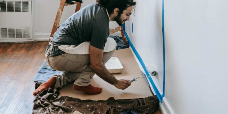Un professionista utilizza un rullo per pitturare le pareti esterne di un edificio, con ponteggi in primo piano